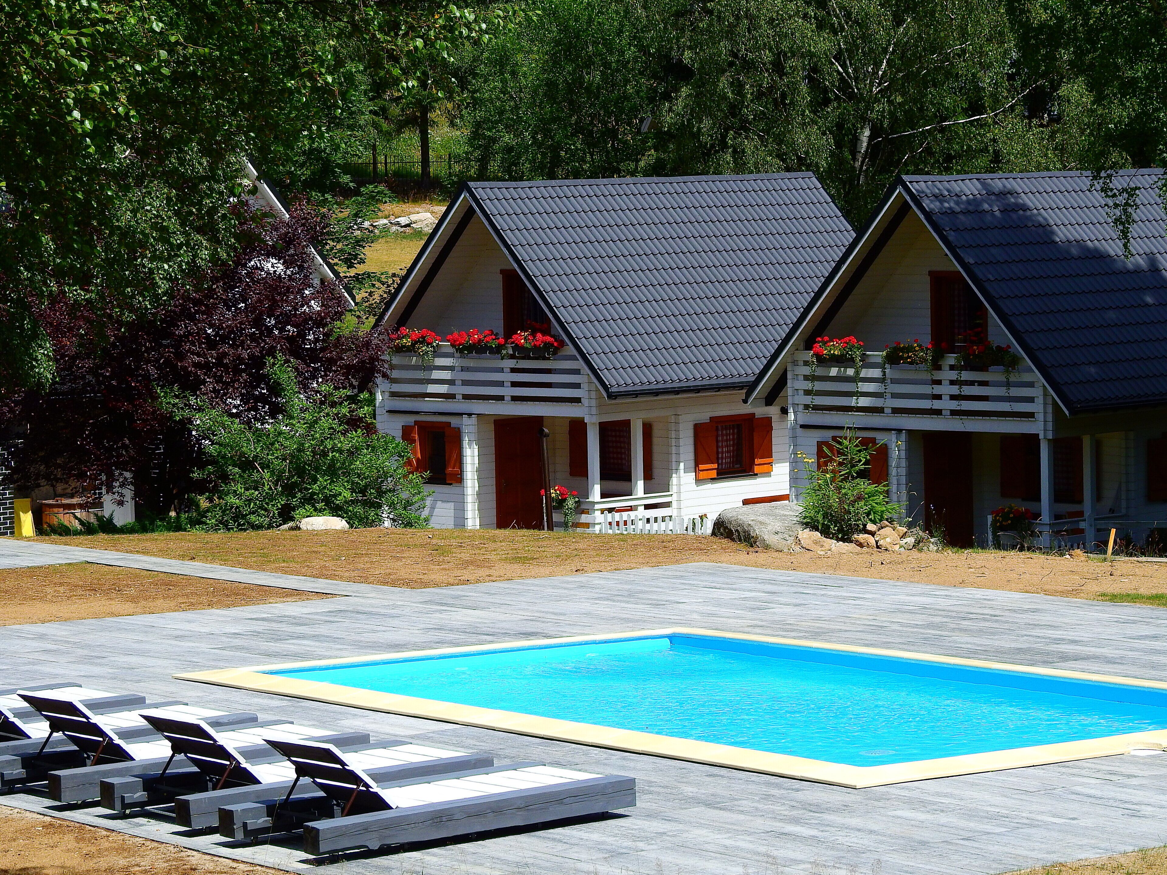 Ein zweistöckiges Gebäude mit Schwimmbecken und Liegestühlen.