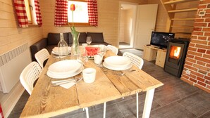 A wooden dining table set with plates, glasses, and a vase with a flower. - Cozy cottage house in the idyllic oasis by the stream (Szklarska Poręba)