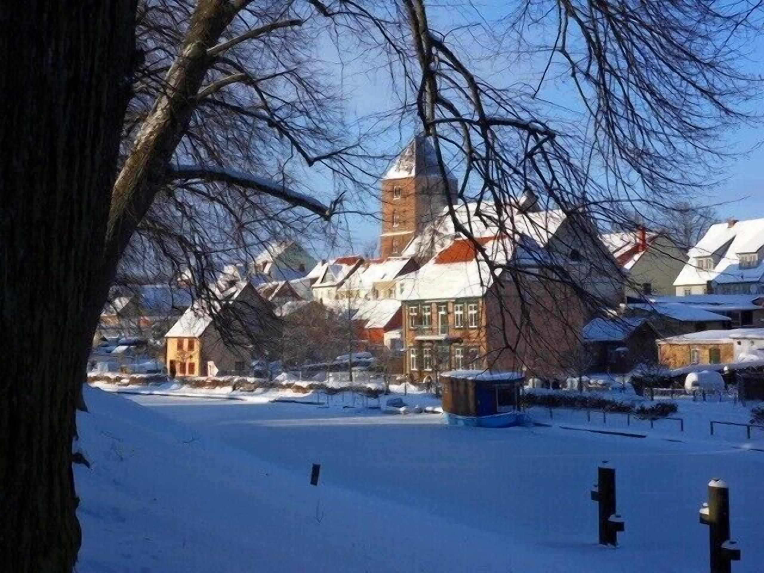 A snow-covered village with traditional buildings, including a church with a tall steeple.