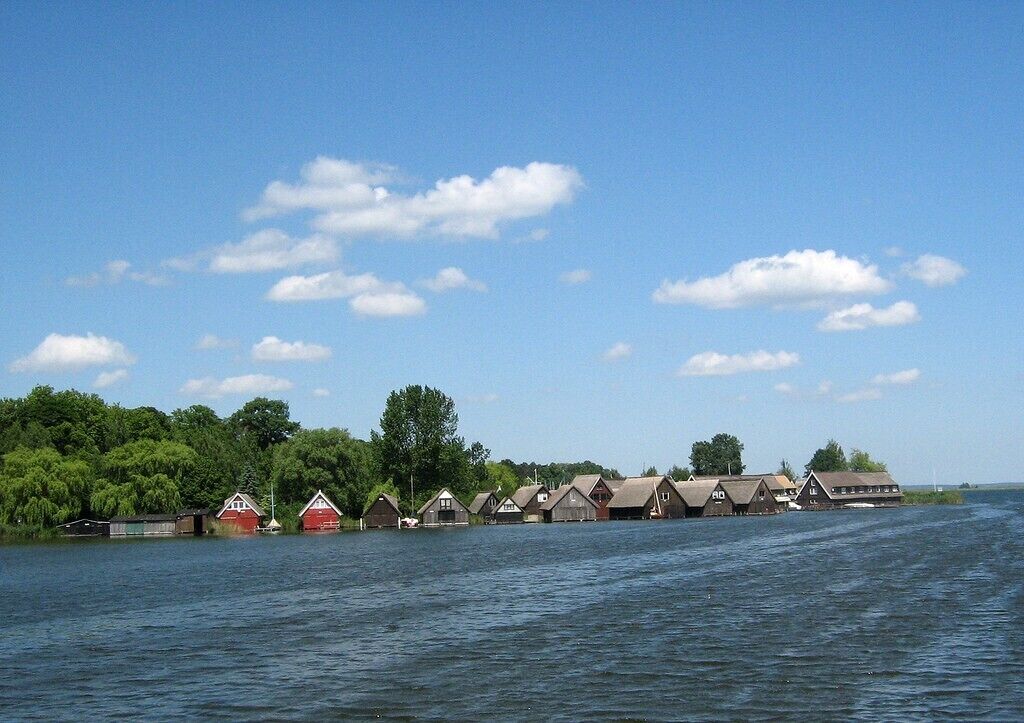 A row of wooden cabins by a lake with a clear sky.