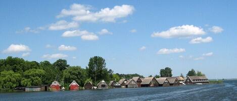 A row of wooden cabins by a lake with a clear sky.