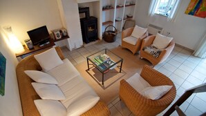 Ein gemütliches Wohnzimmer mit einer Couch, zwei Sesseln, einem Couchtisch, einem Kamin und einem Bücherregal.