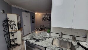 A compact kitchen with a granite countertop, stainless steel sink, and white cabinets. -  Condo/apt. near Disney, Universal, 3 pools, WIFI,free Parking !  (Florida)