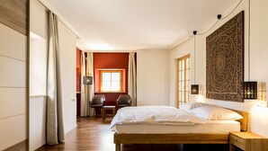 Ein Schlafzimmer mit einem hölzernen Bett, einem kleinen Tisch, zwei Stühlen, einem Fenster und einer Wanddekoration.