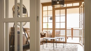 Ein Zimmer mit einer großen Glasschiebetür, die auf einen Balkon führt, einem weißen, flauschigen Teppich und einer modernen Lampenleuchte.