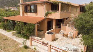 A two-story house with a stone patio, outdoor seating, and a view of the surrounding greenery. - Holiday Home in Vinišće with Seaview, Balcony, Air condition, WIFI (3484-1) (Vinišce)