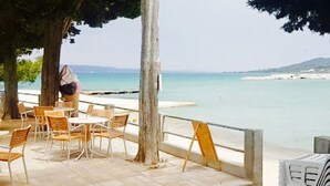 An outdoor seating area with tables and chairs, a tree, and a view of the sea. - Villa / finca with beautiful terrace & large garden, 5 minutes to the beach, Dalmatia (Ždrelac)