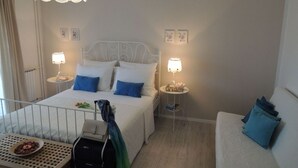 Hotellihuone, jossa on sänky, yöpöydät, matkalaukku ja pieni pöytä, jonka päällä on lautanen ruokaa.