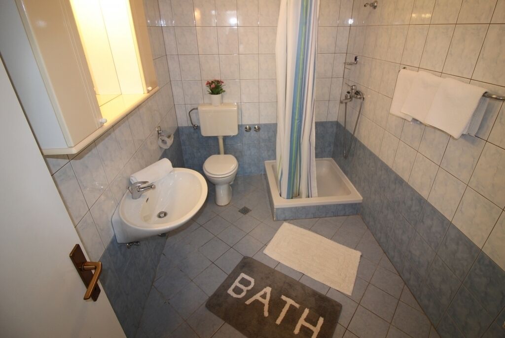 Une salle de bain équipée d’un lavabo, de toilettes, d’une baignoire et d’un rideau de douche.