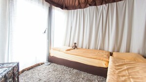 Una camera da letto con un letto, un giocattolo di legno e una valigia.