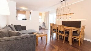 Un soggiorno con un divano grigio, un tavolo da pranzo in legno con sedie e un lampadario.