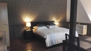 Un dormitorio con cama, dos lámparas de noche, cabecero de madera y suelo de madera.