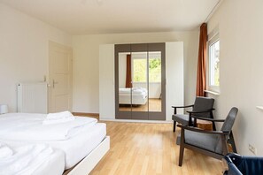 Een hotelkamer met een bed, een stoel, een raam en een schuifdeur naar een balkon.