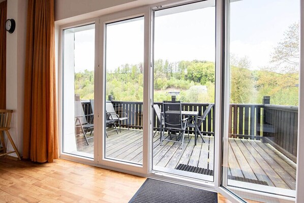 A room with a large sliding glass door leading to an outdoor deck with a table and chairs.