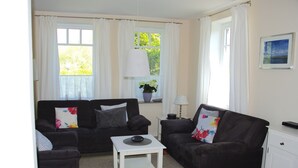 A living room with two black sofas, a white coffee table, and a white cabinet. - Exclusive Friesenhaus * * * * * with sea views, sauna, wireless, disabled (Husum/Schobüll)
