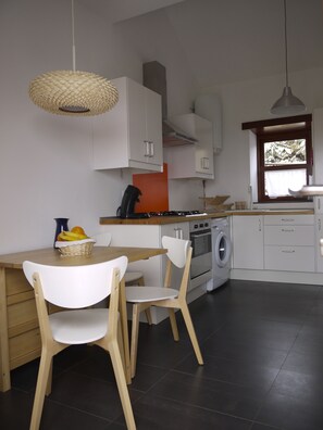 A modern kitchen with white cabinets, a wooden dining table, and a built-in washing machine. - Newly restored in 2012, rural environment, fully connected, very well connected (Isora)