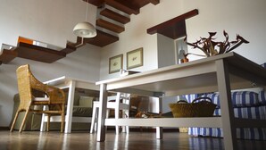 A room with a high ceiling, wooden beams, a white table, wicker furniture, and a blue-striped sofa. - Newly restored in 2012, rural environment, fully connected, very well connected (Isora)