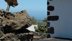 A stone building with a tiled roof, a rocky foreground, and a clear blue sky. - Newly restored in 2012, rural environment, fully connected, very well connected (Isora)