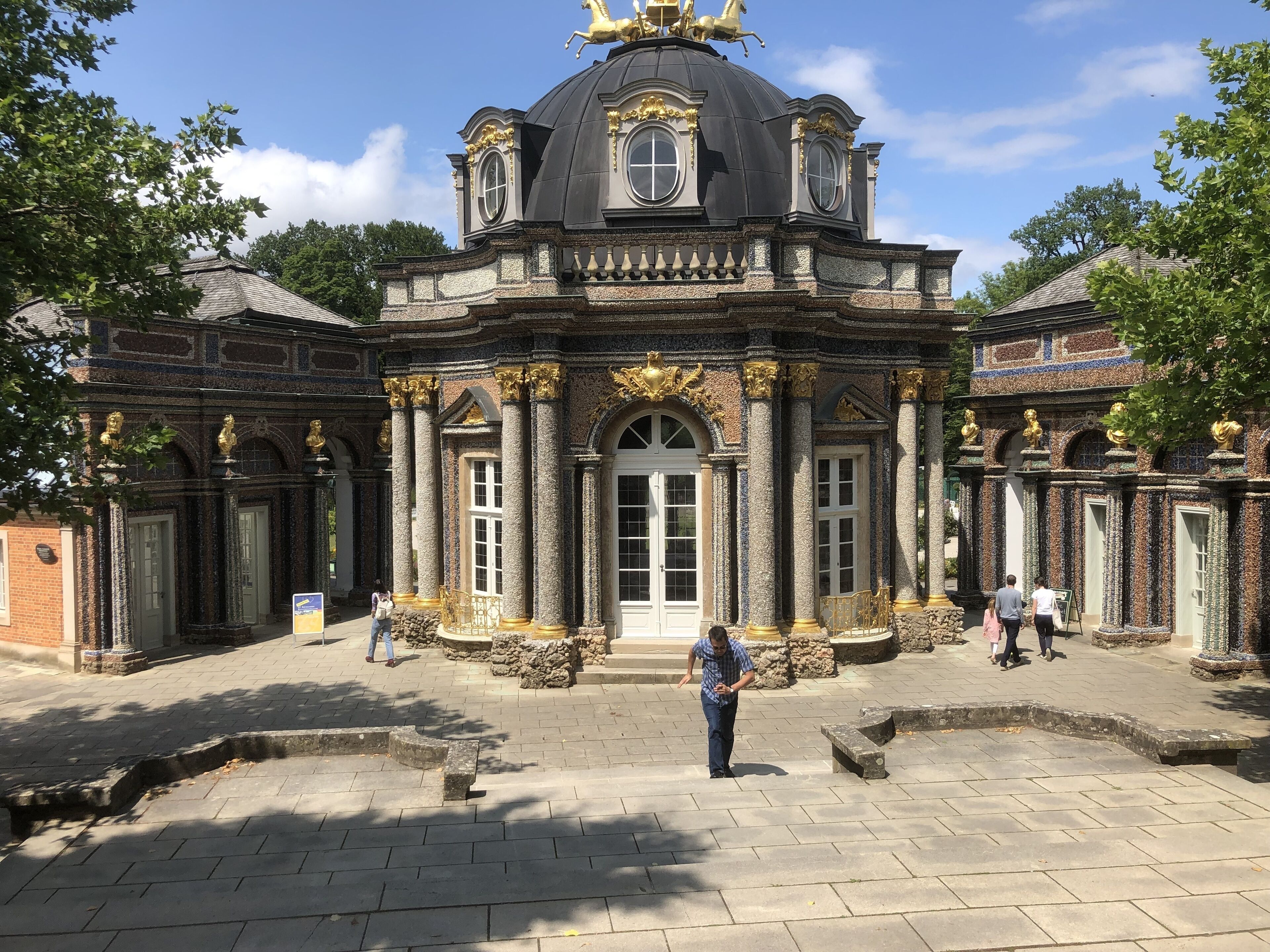 Ein historisches Gebäude mit aufwendigen Säulen und einer zentralen Kuppel, das einen prunkvollen Eingang und einen Innenhof zeigt.