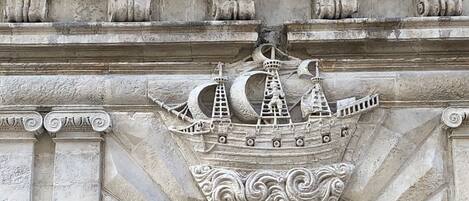 A stone facade with a decorative ship motif above a window.