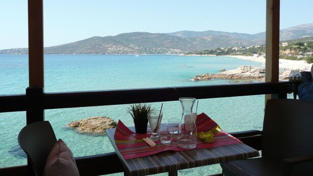 A table with a clear view of a coastal landscape, including a beach and mountains. - House redone in VICO- WIFI- 15mns Beaches of SAGONE (Vico)