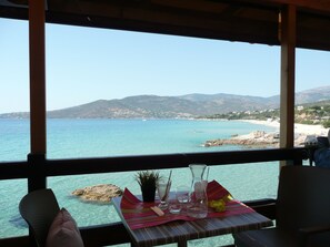 A table with a clear view of a coastal landscape, including a beach and mountains. - House redone in VICO- WIFI- 15mns Beaches of SAGONE (Vico)