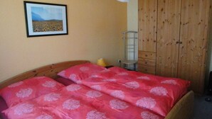 A bedroom with a wooden bed, a wardrobe, and a framed picture on the wall.