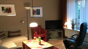 A living room with a sofa, a coffee table with a red rug, a TV, and a black chair.