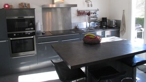Una cocina moderna con electrodomésticos de acero inoxidable, una isla central y una lámpara colgante.