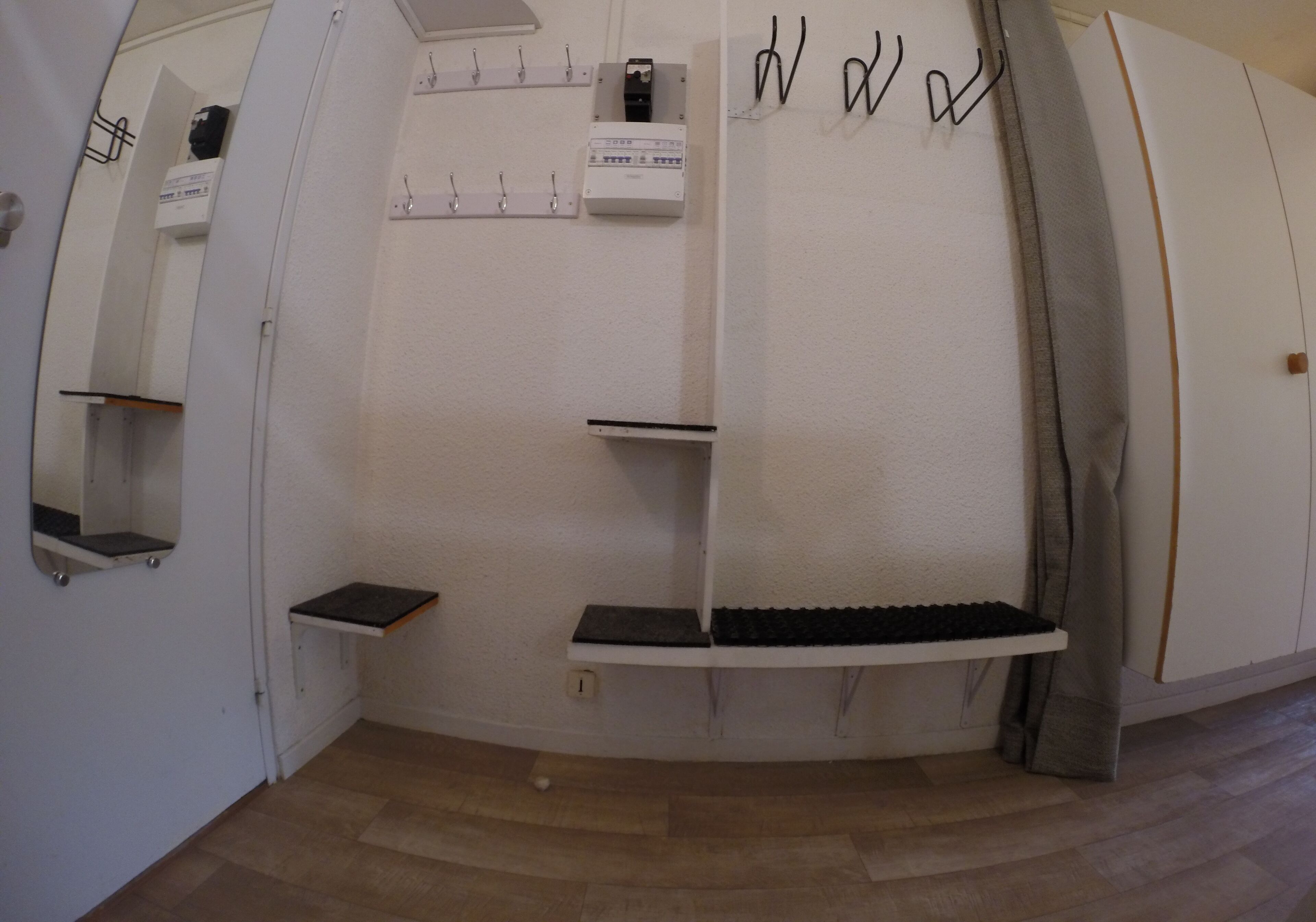 A room with a curved wall, a built-in shelf, a small table, and a mirror.
