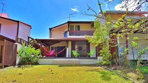 Um imóvel residencial com um alpendre coberto, gramado e um pequeno jardim.