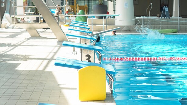 En swimmingpool med springtårne og en livredderstand.