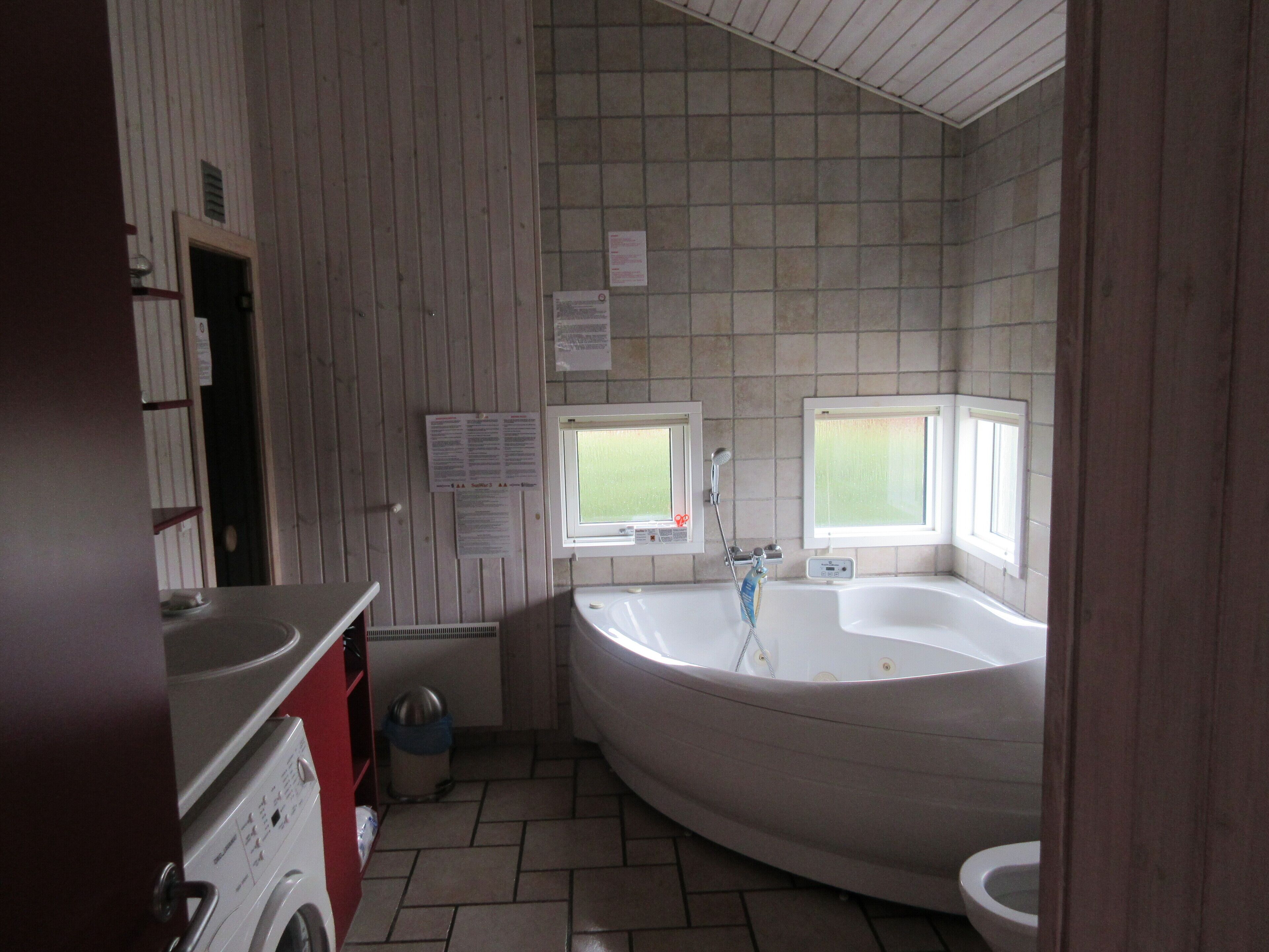 A bathroom with a large bathtub, a toilet, and a washing machine.