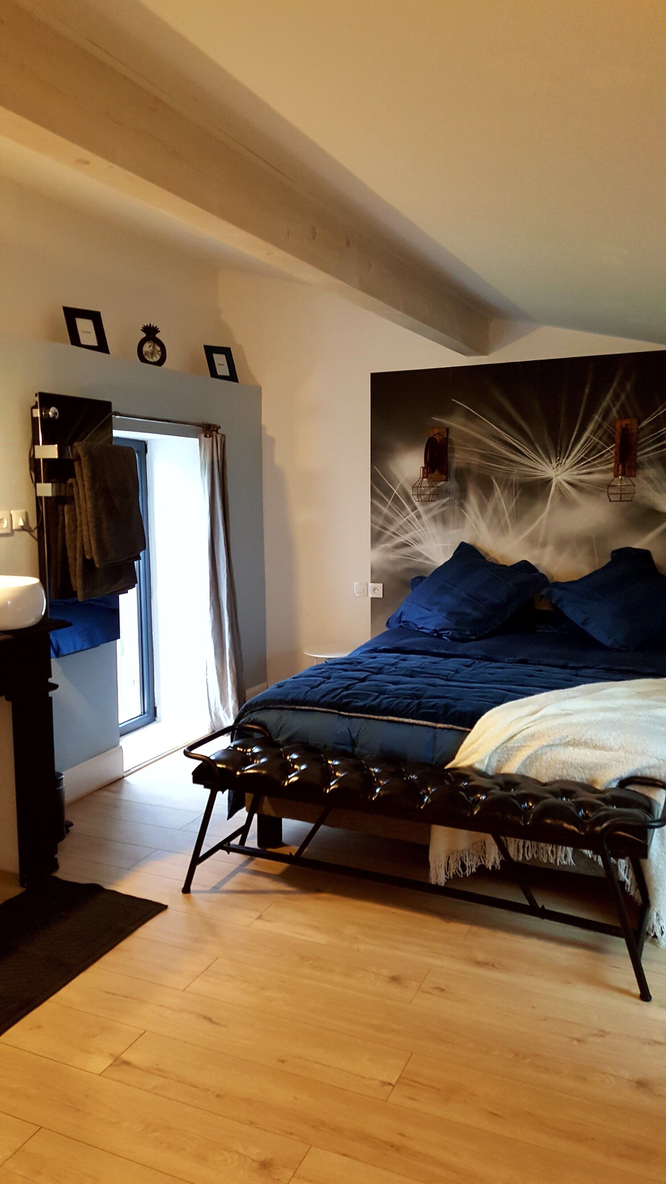 A bedroom with a bed, a bedside table, a window, and a door.