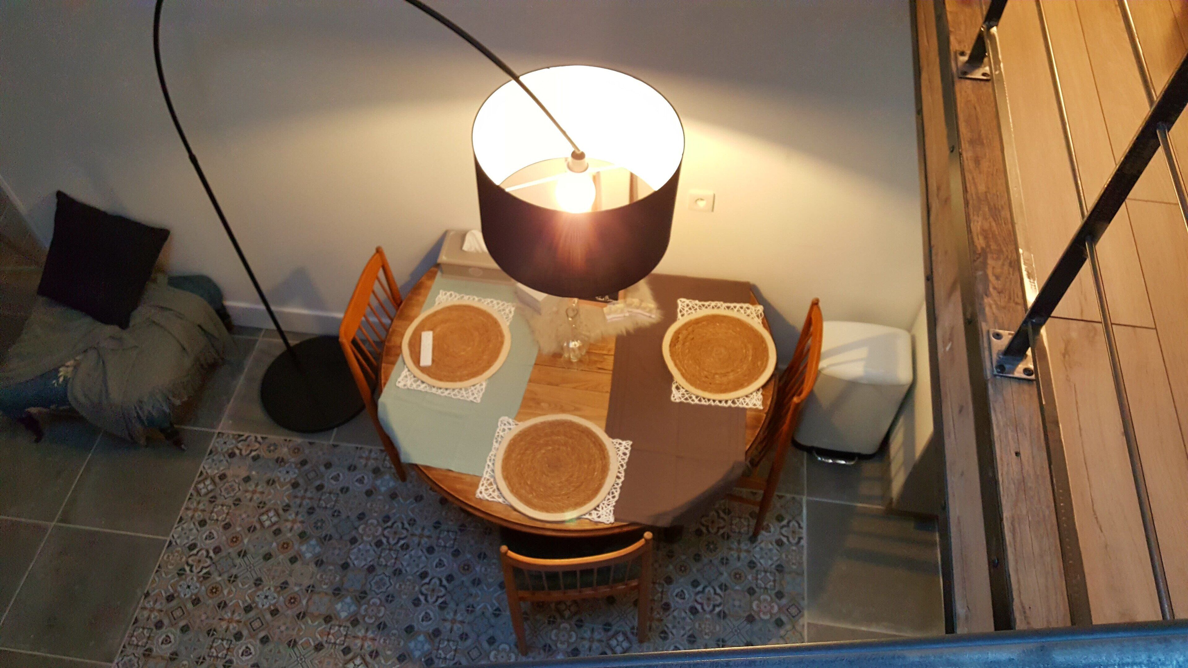 Une table à manger avec quatre chaises, une lampe et un tapis à motifs.