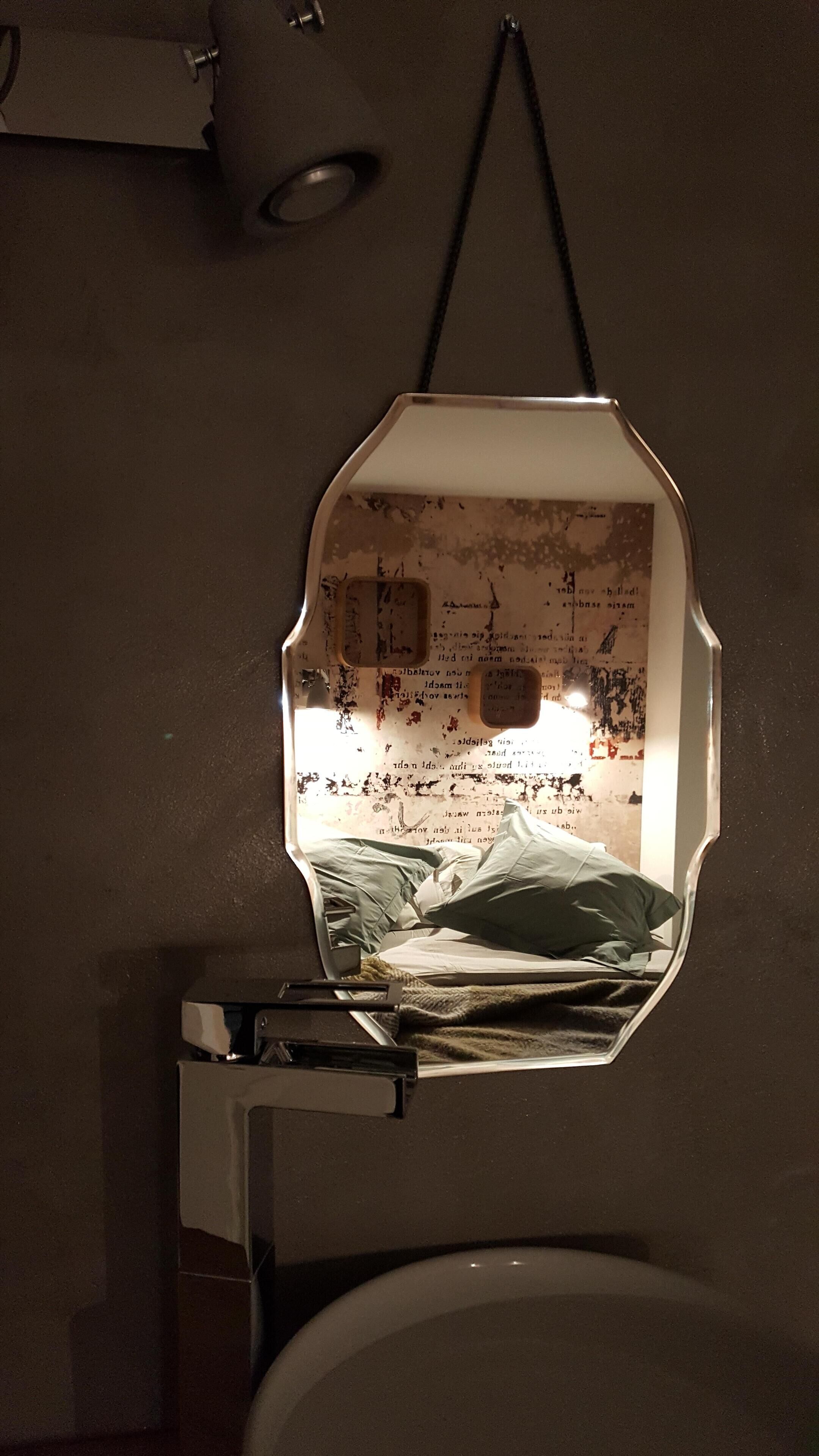 Un baño con un espejo que refleja una habitación desordenada.