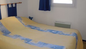 A room with a bed, a window with curtains, a radiator, and a hanging light fixture.