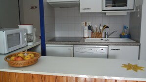 A compact kitchen with white appliances, a granite countertop, and a wooden cabinet.
