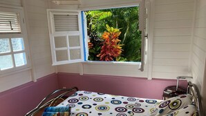 A small, single-bed room with a window overlooking a garden. - Villa with private saltwater pool and panoramic view of the sea and Diamond Rock. (RIVIERE SALEE)