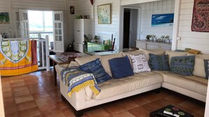 A living room with a beige sofa, a coffee table, and a dining area with a table and chairs. - Villa with private saltwater pool and panoramic view of the sea and Diamond Rock. (RIVIERE SALEE)