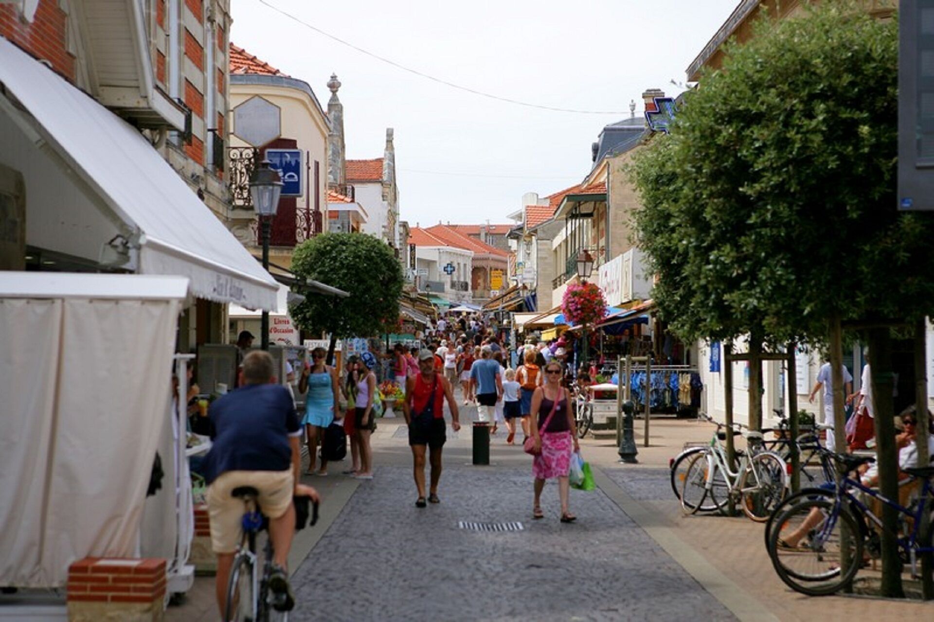 Eine Kopfsteinpflasterstraße gesäumt von Geschäften und Häusern, mit parkenden Fahrrädern und Fußgängern.