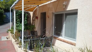 Un bâtiment doté d’un porche abrité, d’une fenêtre et d’une plante en pot.