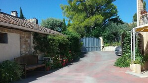 Une rue étroite, avec un bâtiment en pierre sur le côté gauche, un banc et des plantes en pot.