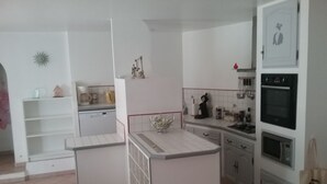 Une cuisine avec des meubles blancs, un lave-vaisselle, une cuisinière et un four à micro-ondes.