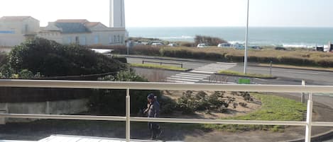 Une vue sur la côte avec un phare, une route avec un passage piéton et des voitures garées.