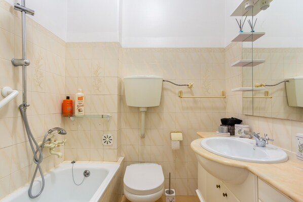 Une salle de bain équipée d’une baignoire, de toilettes, d’un lavabo et d’une douche.