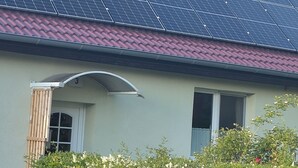 A house with solar panels on the roof, a wooden fence, and a number '3' on the wall. - New apartment in the middle of the lake district ideal for active recreation (Blankensee)