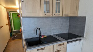 A compact kitchen with wooden cabinets, a black sink, and a built-in dishwasher.