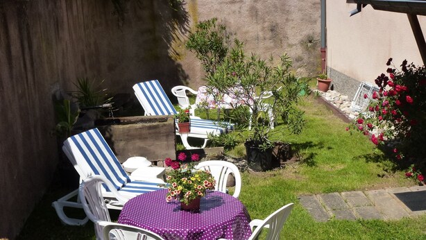 A patio with white plastic chairs and a table covered with a purple polka dot tablecloth. - highland cottage (Grendelbruch)