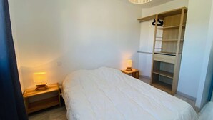 A bedroom with a bed, two bedside tables with lamps, a wardrobe, and a hanging rack.